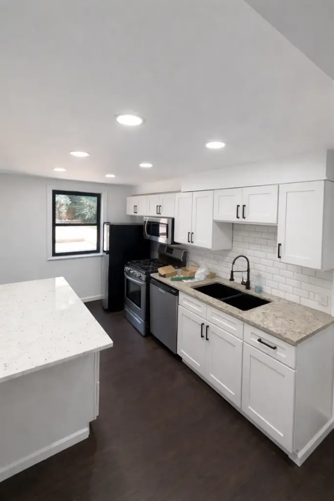 Fully renovated modern kitchen with white shaker cabinets, quartz countertops, stainless steel appliances, recessed lighting, and dark hardwood flooring