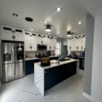 Modern kitchen remodel featuring white shaker cabinets, quartz waterfall island, stainless steel appliances, and marble tile flooring installed by DLS Construction LLC.
